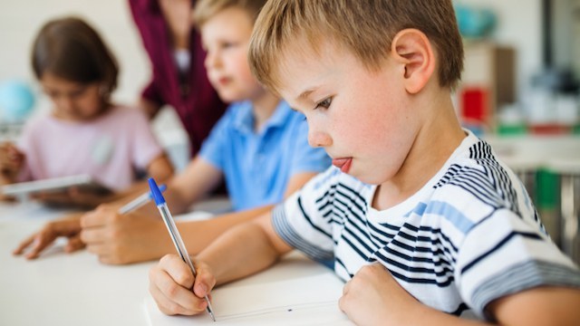 Schulkind schreibt konzentriert in sein Heft.