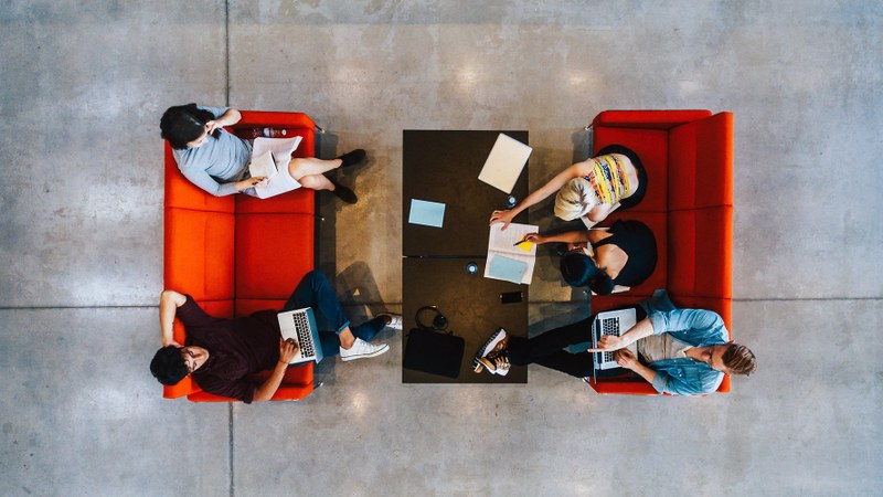 Foto von oben auf Studierende, die sich gegenüber auf Sofas sitzen
