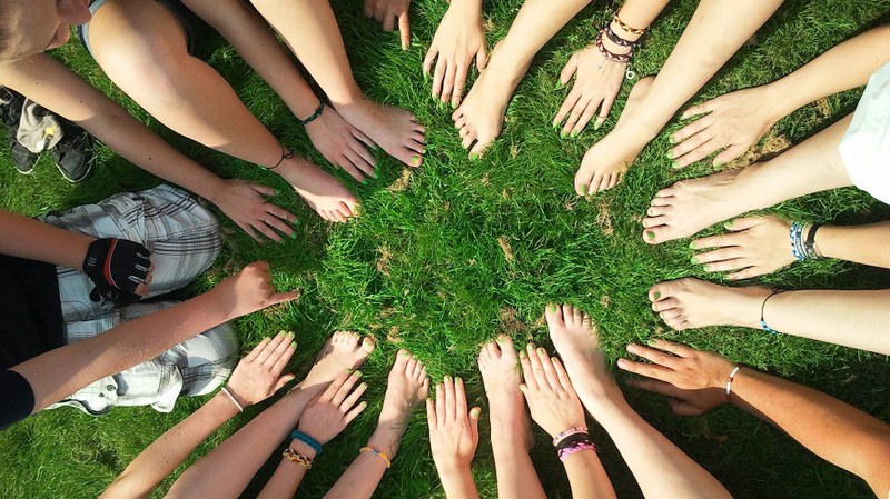 Hände und Füsse bilden einen Kreis im Gras