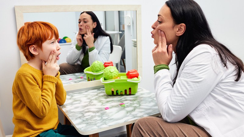 Eine Logopädin in der Therapiestunde mit einem Jungen