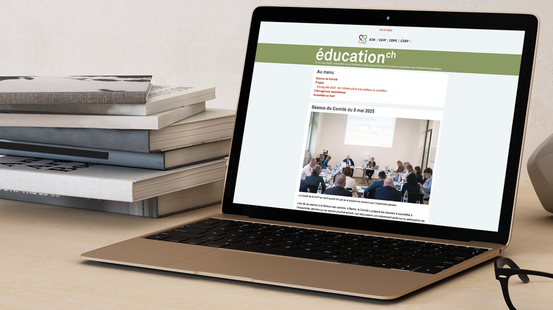 Laptop ouvert, montrant l’infolettre de la CDIP sur son écran; pile de livres posée à gauche du laptop