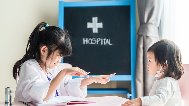 Deux filles d'origine asiatique jouent à la patiente et au médecin dans l'école de l'hôpital.