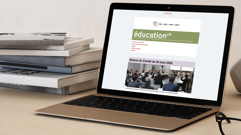 Laptop ouvert, montrant l’infolettre de la CDIP sur son écran; pile de livres posée à gauche du laptop