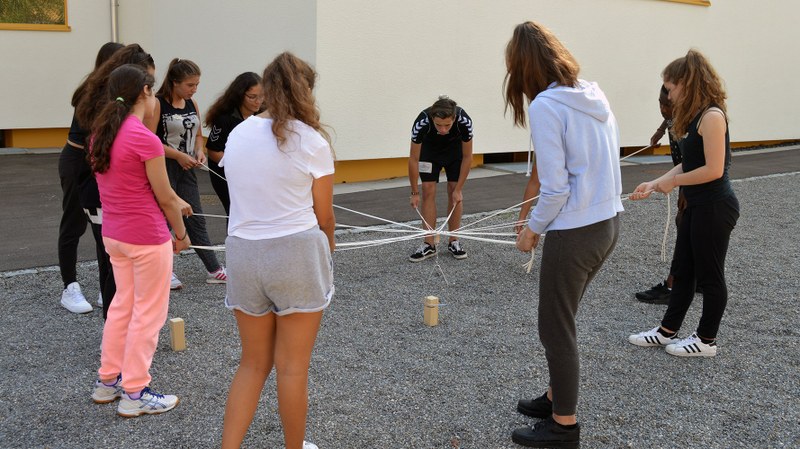 Des jeunes sont en cercle et font un exercice de team building