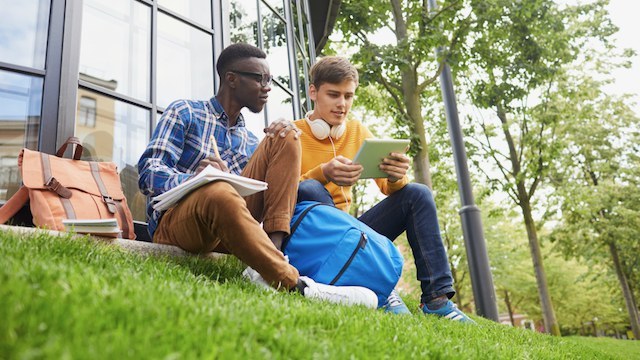 Dus students sesan or en il liber davant la scola auta
